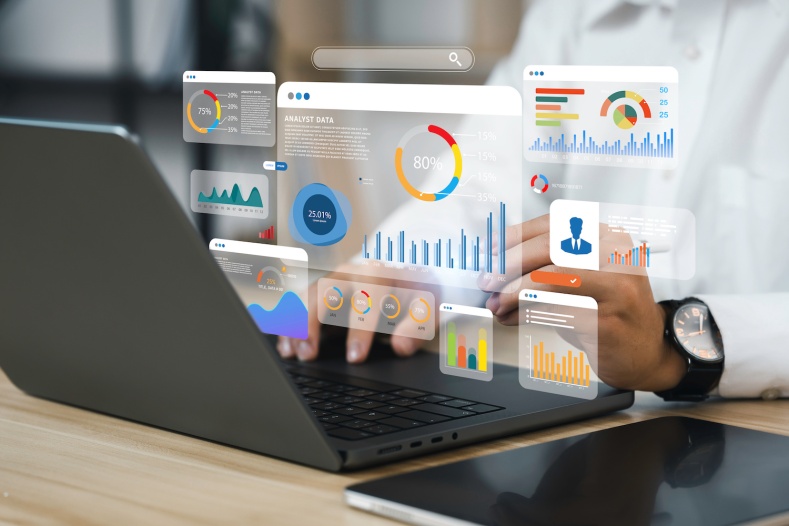 A businessperson works at a laptop computer, with data graphics overlaid.